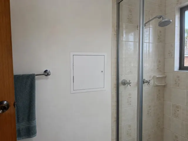 Small white access panel on a bathroom wall beside a tiled shower in Cronulla